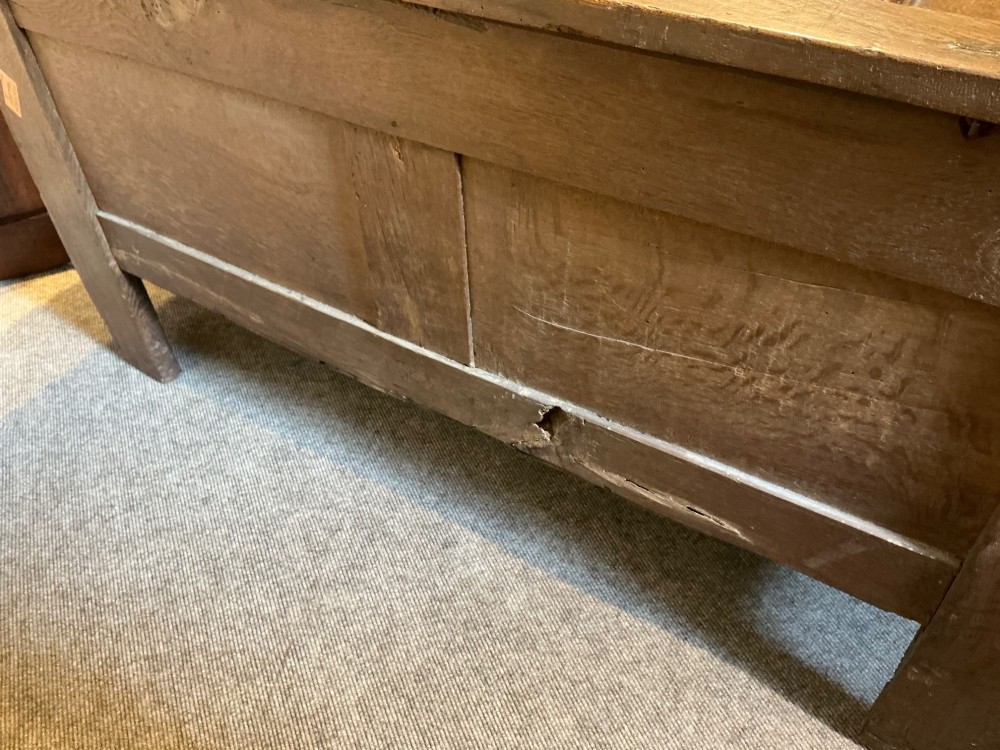 A 17th-century carved oak coffer with a four-panel lid, carved lunette top rail, roundel carved front panels, and a central iron lockplate. View XI