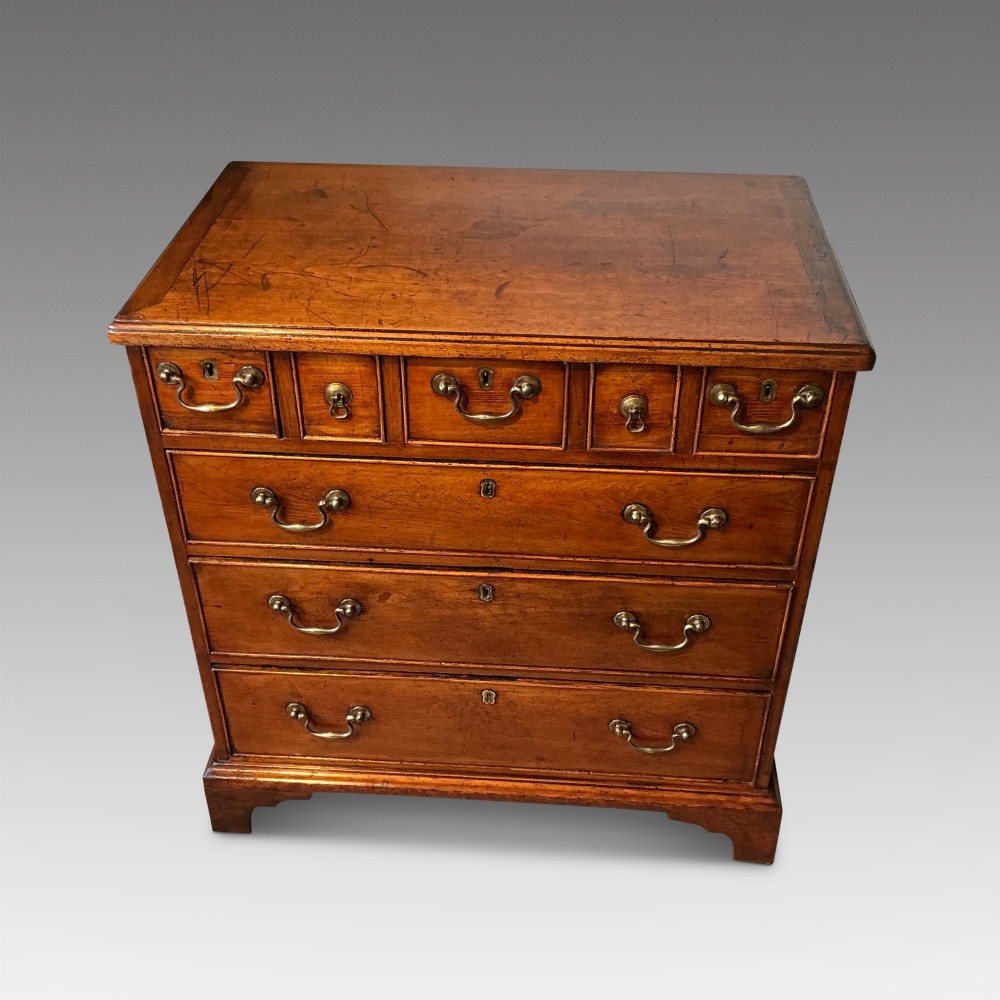 A Georgian cedar wood chest of drawers featuring multiple drawer compartments, brass swan-neck handles, and bracket feet. View II