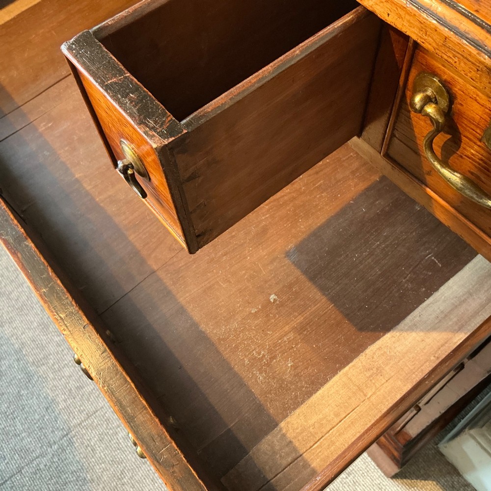 A Georgian cedar wood chest of drawers featuring multiple drawer compartments, brass swan-neck handles, and bracket feet. View VI