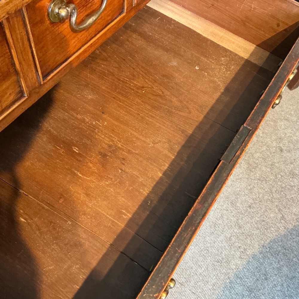 A Georgian cedar wood chest of drawers featuring multiple drawer compartments, brass swan-neck handles, and bracket feet. View VII