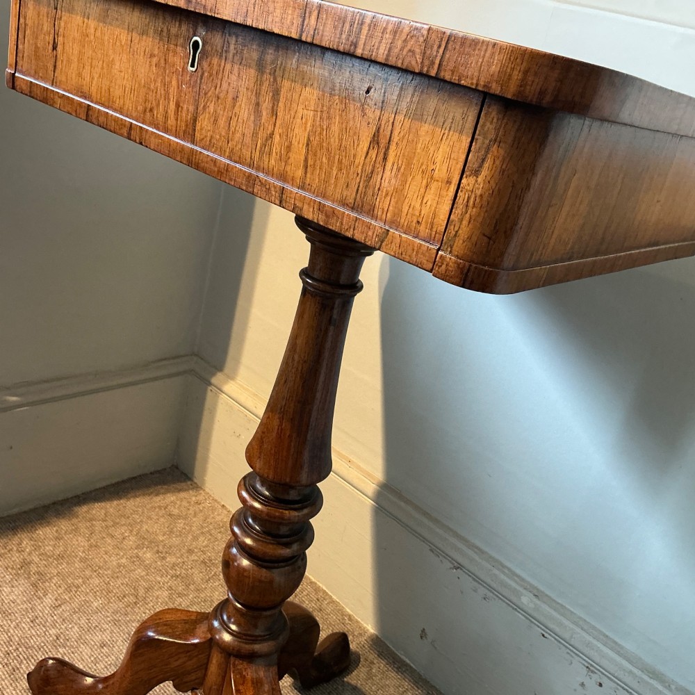 An antique rosewood pedestal table featuring a rectangular top with rounded corners, a keyhole in the frieze, a turned central stem, and a tripod base. View V