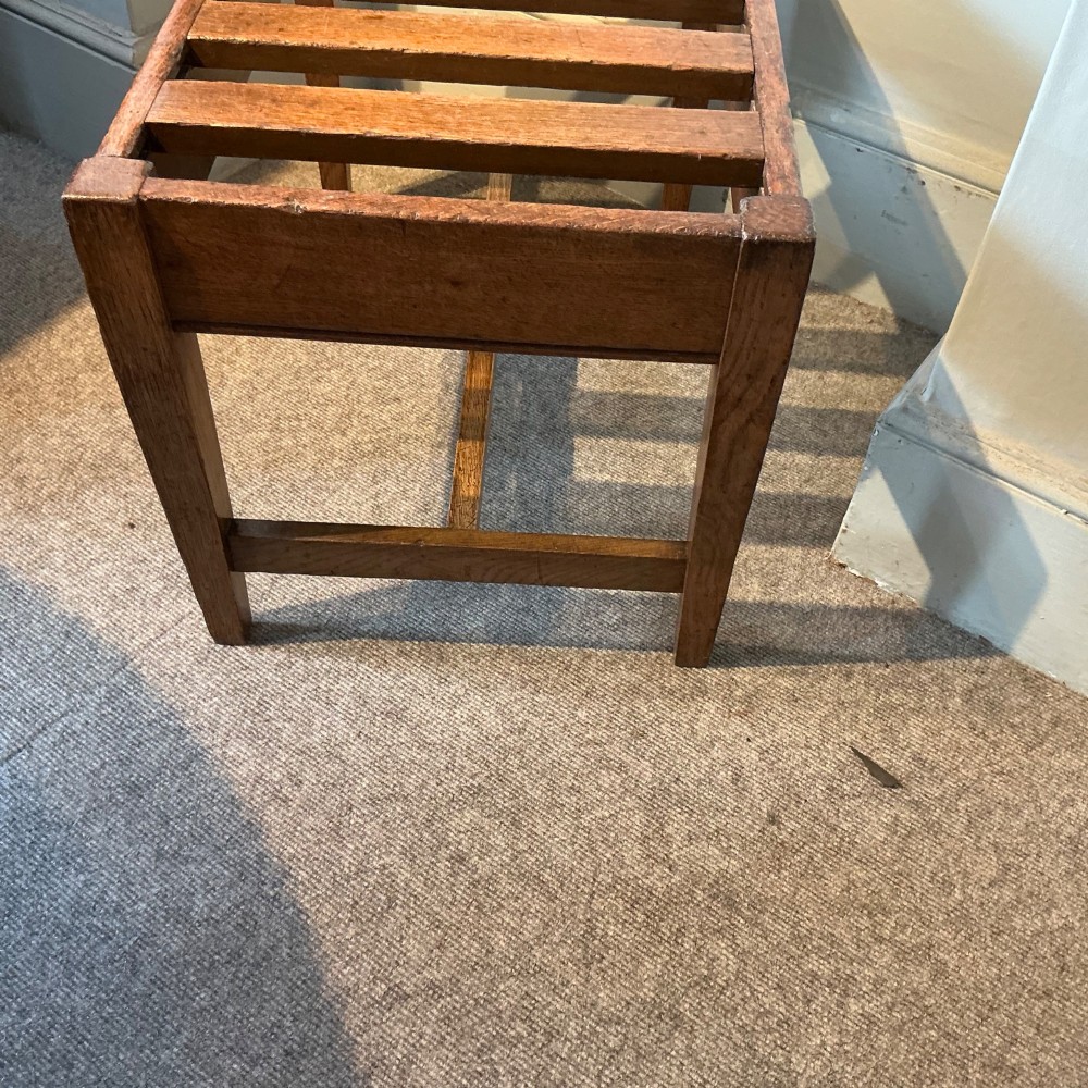 A solid oak antique luggage rack featuring five rectangular top slats supported by square legs and cross stretchers. View V