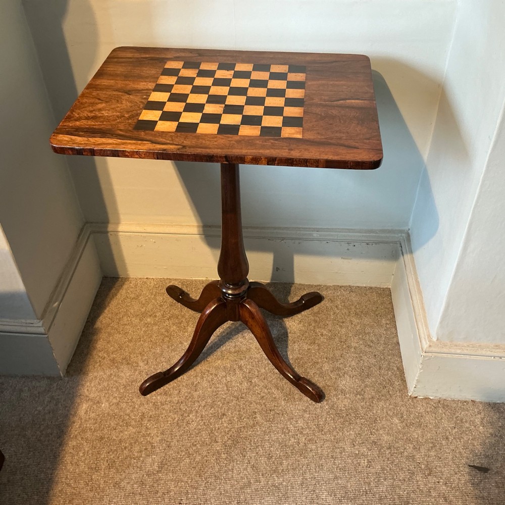 An antique dark wood pedestal chess table featuring an inlaid checkerboard surface top and a turned stem on four splayed legs. View II