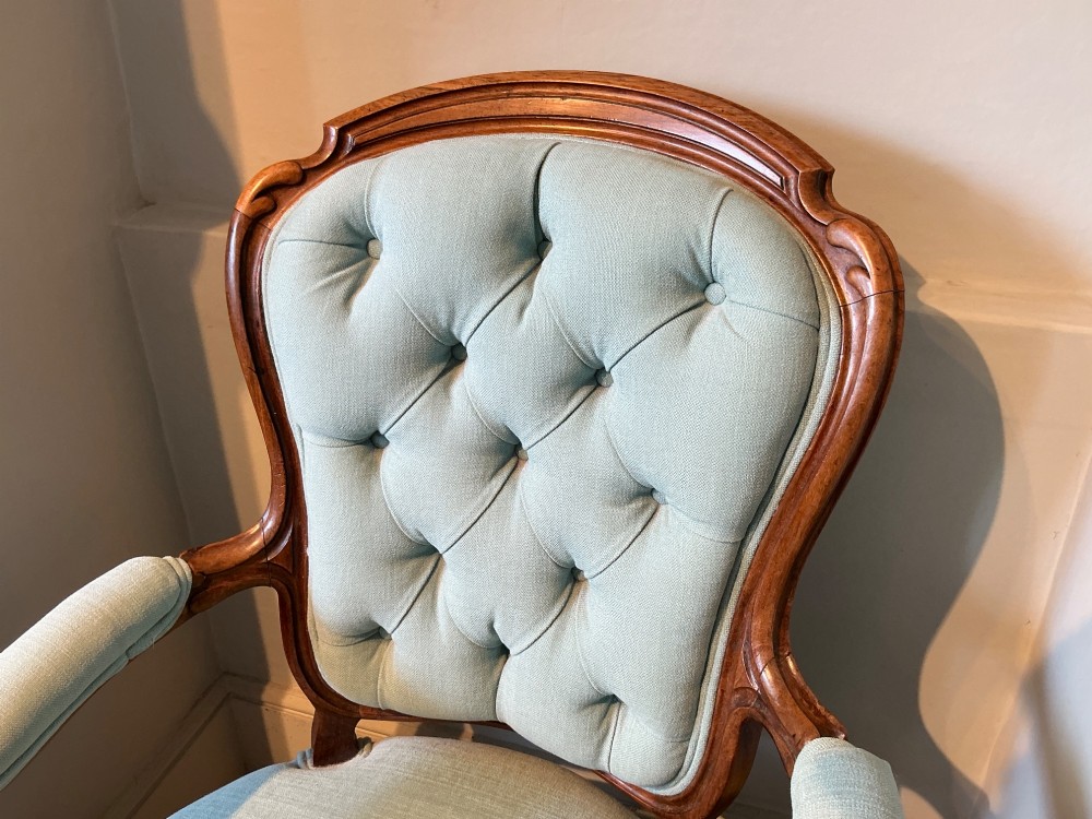 A Victorian carved rosewood open armchair featuring light blue button-tufted upholstery, padded armrests, and cabriole legs on brass castors. View II