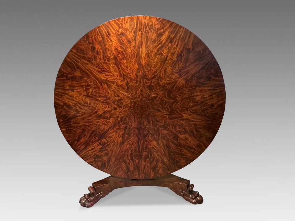 A circular antique mahogany centre table featuring a radially segmented flame veneer top supported by a central pedestal with carved claw feet. View III