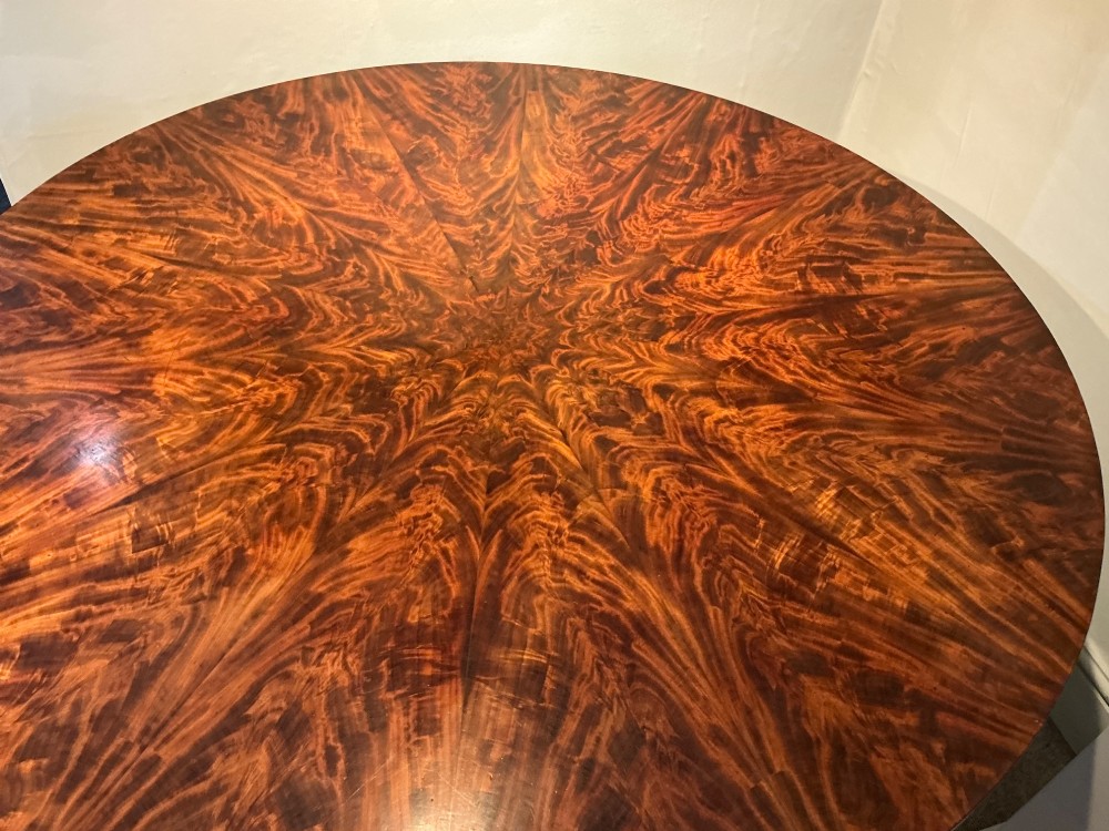 A circular antique mahogany centre table featuring a radially segmented flame veneer top supported by a central pedestal with carved claw feet. View IV
