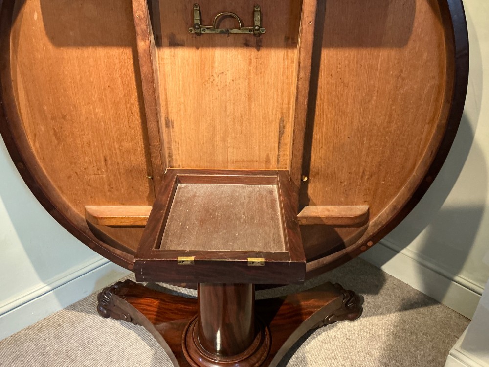A circular antique mahogany centre table featuring a radially segmented flame veneer top supported by a central pedestal with carved claw feet. View VI