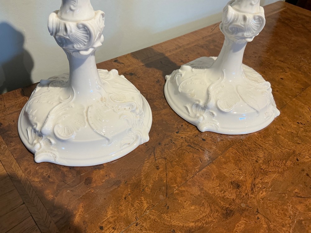 A pair of white glazed porcelain candlesticks featuring ornate Rococo relief moulding and scrollwork bases. View VI