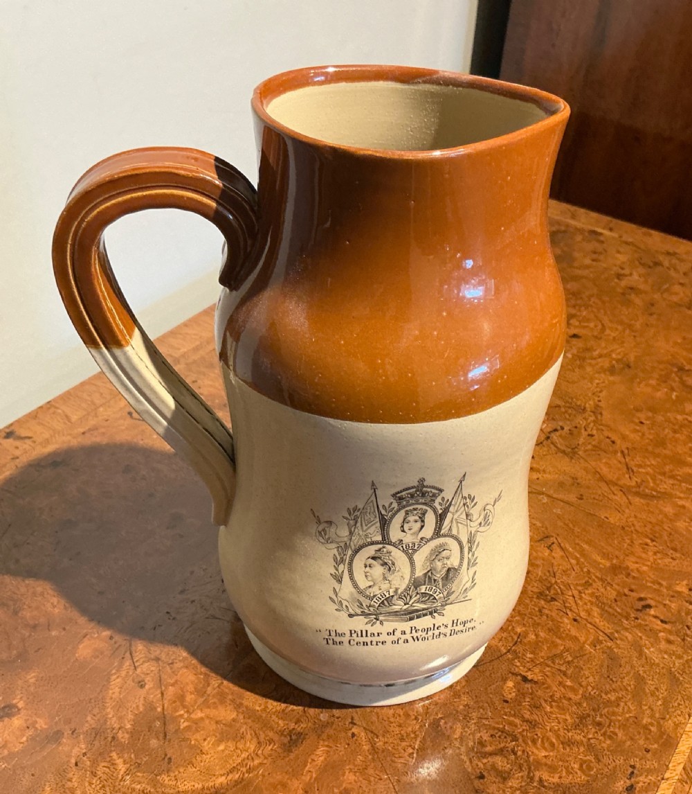 A late nineteenth-century two-tone stoneware jug featuring a rich brown glazed neck, a cream body, and a black transfer-printed portrait commemorating Queen Victoria.