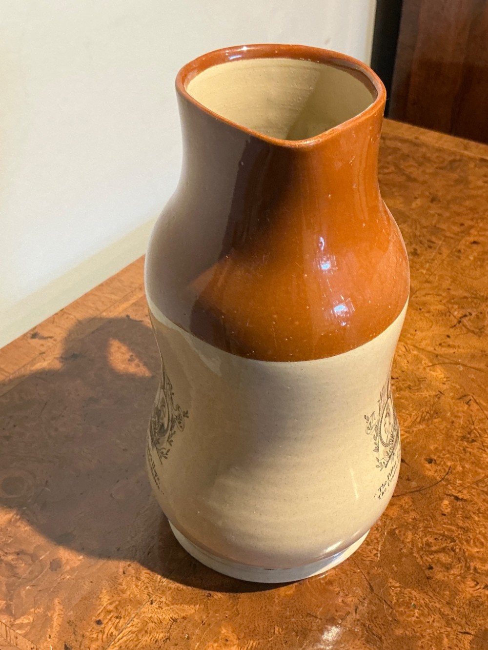 A late nineteenth-century two-tone stoneware jug featuring a rich brown glazed neck, a cream body, and a black transfer-printed portrait commemorating Queen Victoria. View II