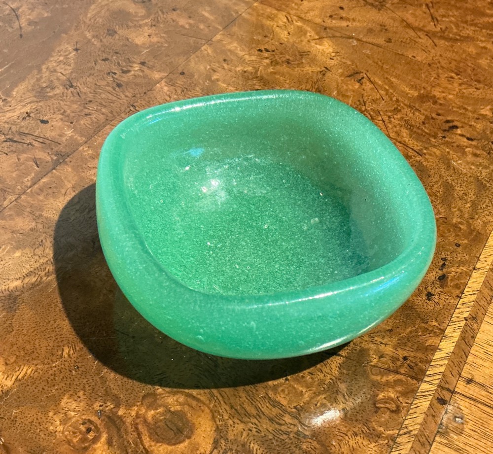 A rounded square green Murano glass dish with thick walls and visible internal micro-bubbles.