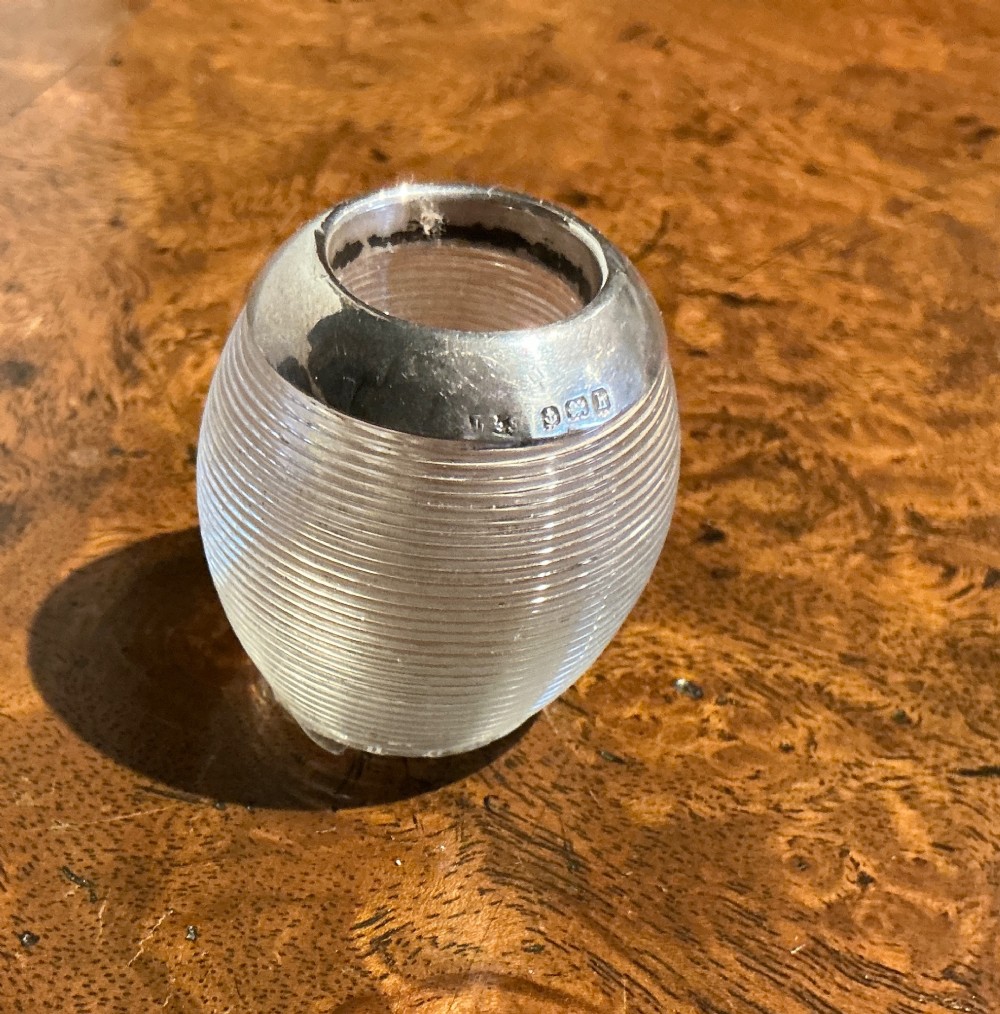 A globular glass match striker featuring a ribbed clear glass body and a hallmarked sterling silver collar around the top opening.