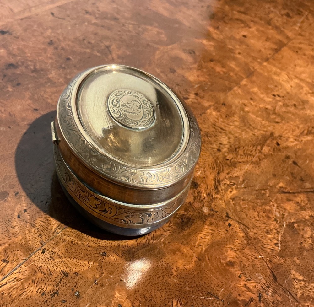 An oval Victorian brass travelling inkwell with detailed foliate engraving around the rim and a central monogram medallion. View II