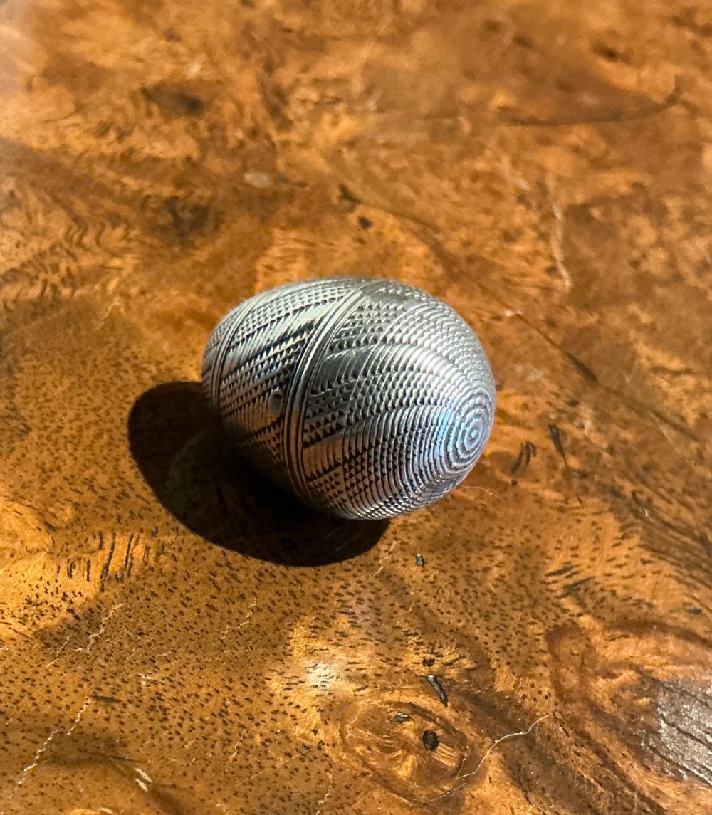 An egg-shaped sterling silver vinaigrette featuring intricate engine-turned geometric engraving and a central opening seam. View II