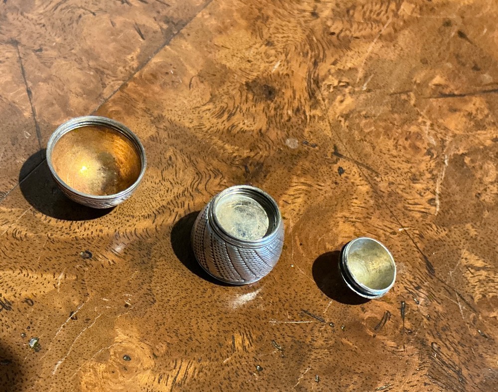 An egg-shaped sterling silver vinaigrette featuring intricate engine-turned geometric engraving and a central opening seam. View IV