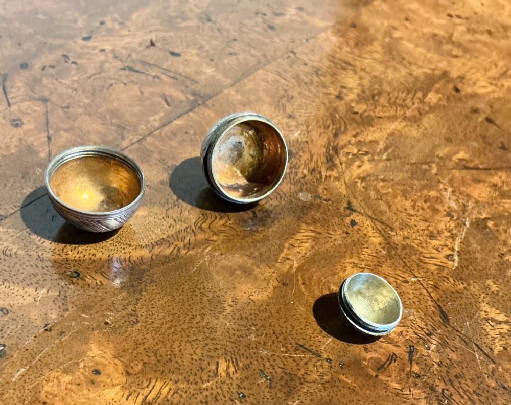 An egg-shaped sterling silver vinaigrette featuring intricate engine-turned geometric engraving and a central opening seam. View V