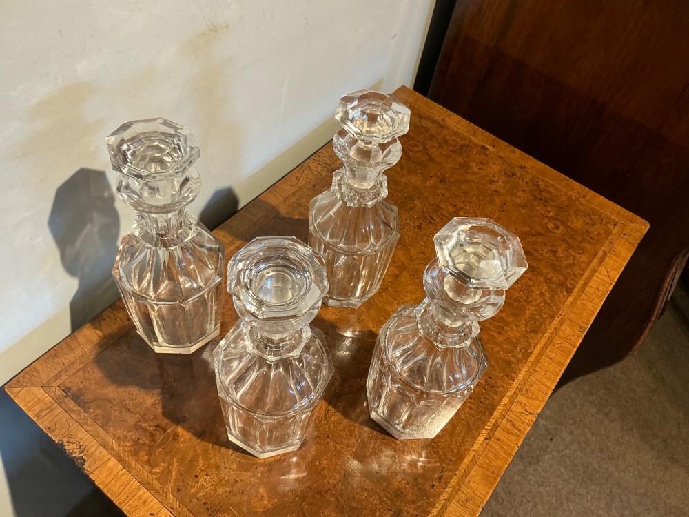 A set of four matching clear cut crystal liqueur decanters featuring panelled bodies and facet-cut stoppers. View II