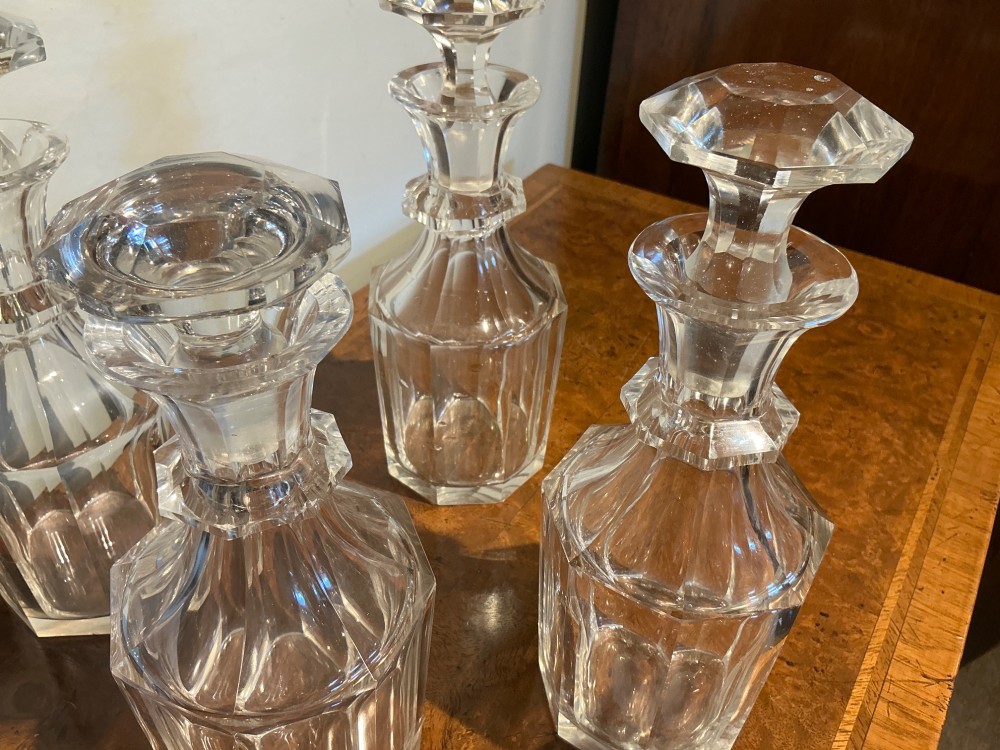 A set of four matching clear cut crystal liqueur decanters featuring panelled bodies and facet-cut stoppers. View IV