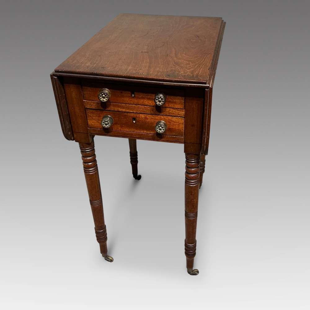 A dark mahogany Georgian Pembroke table featuring two drop leaves, twin drawers with brass knobs, turned legs, and brass castors. View II