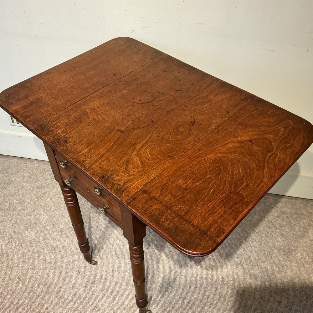 A dark mahogany Georgian Pembroke table featuring two drop leaves, twin drawers with brass knobs, turned legs, and brass castors. View V
