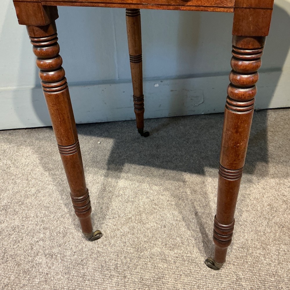 A dark mahogany Georgian Pembroke table featuring two drop leaves, twin drawers with brass knobs, turned legs, and brass castors. View VII