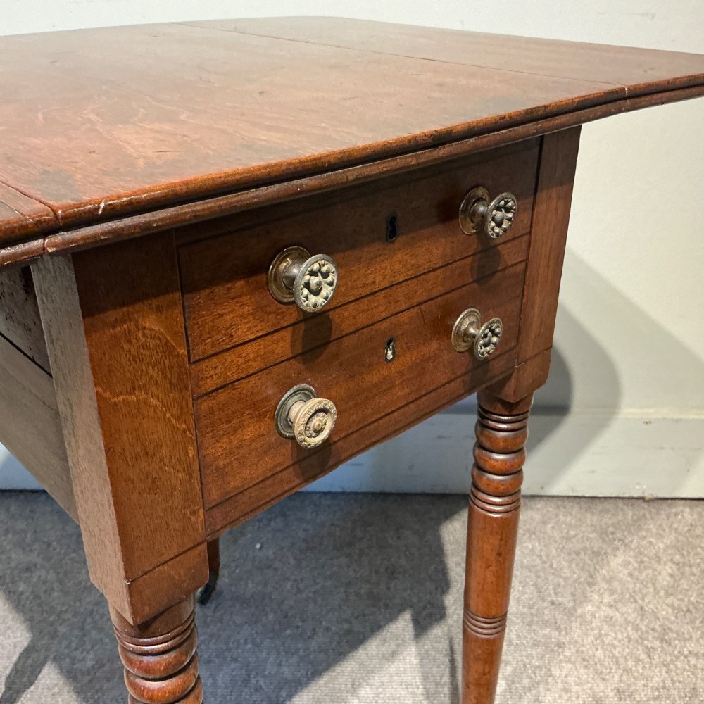 A dark mahogany Georgian Pembroke table featuring two drop leaves, twin drawers with brass knobs, turned legs, and brass castors. View IX