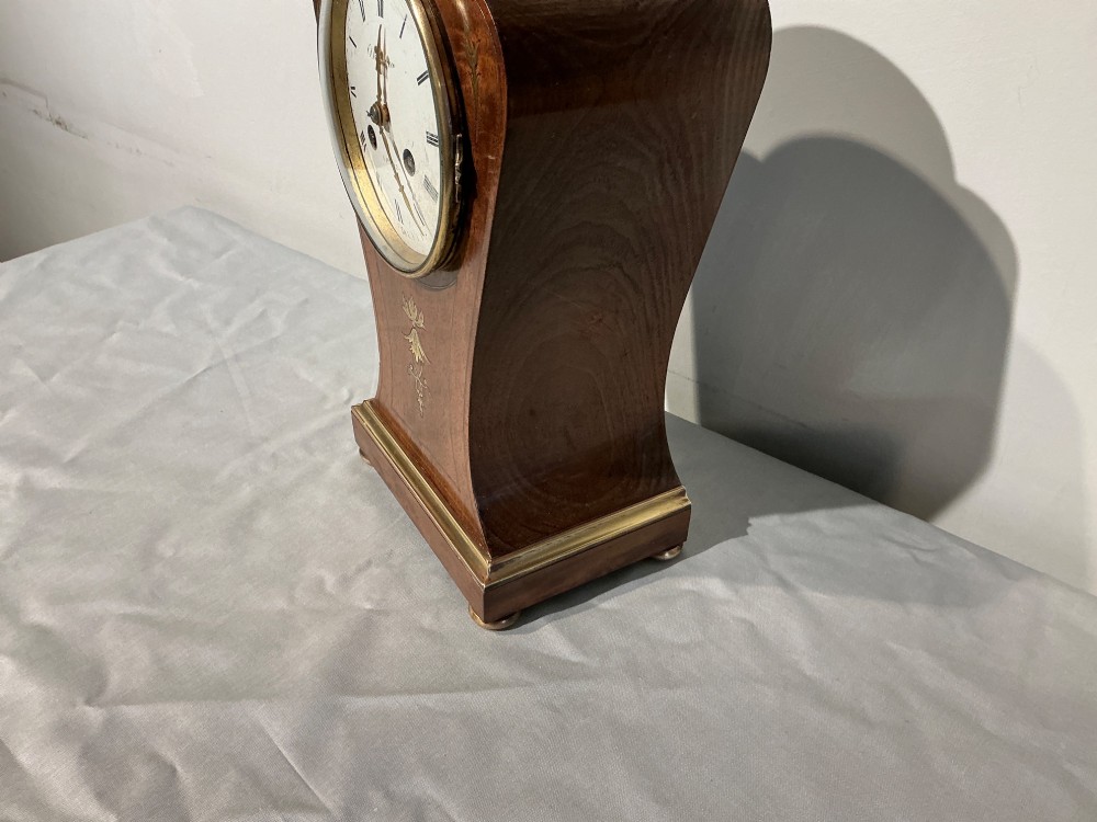 An antique balloon-shaped mahogany mantel clock featuring inlaid brass floral details, a white enamel dial with Roman numerals, and a brass-trimmed plinth base. View V