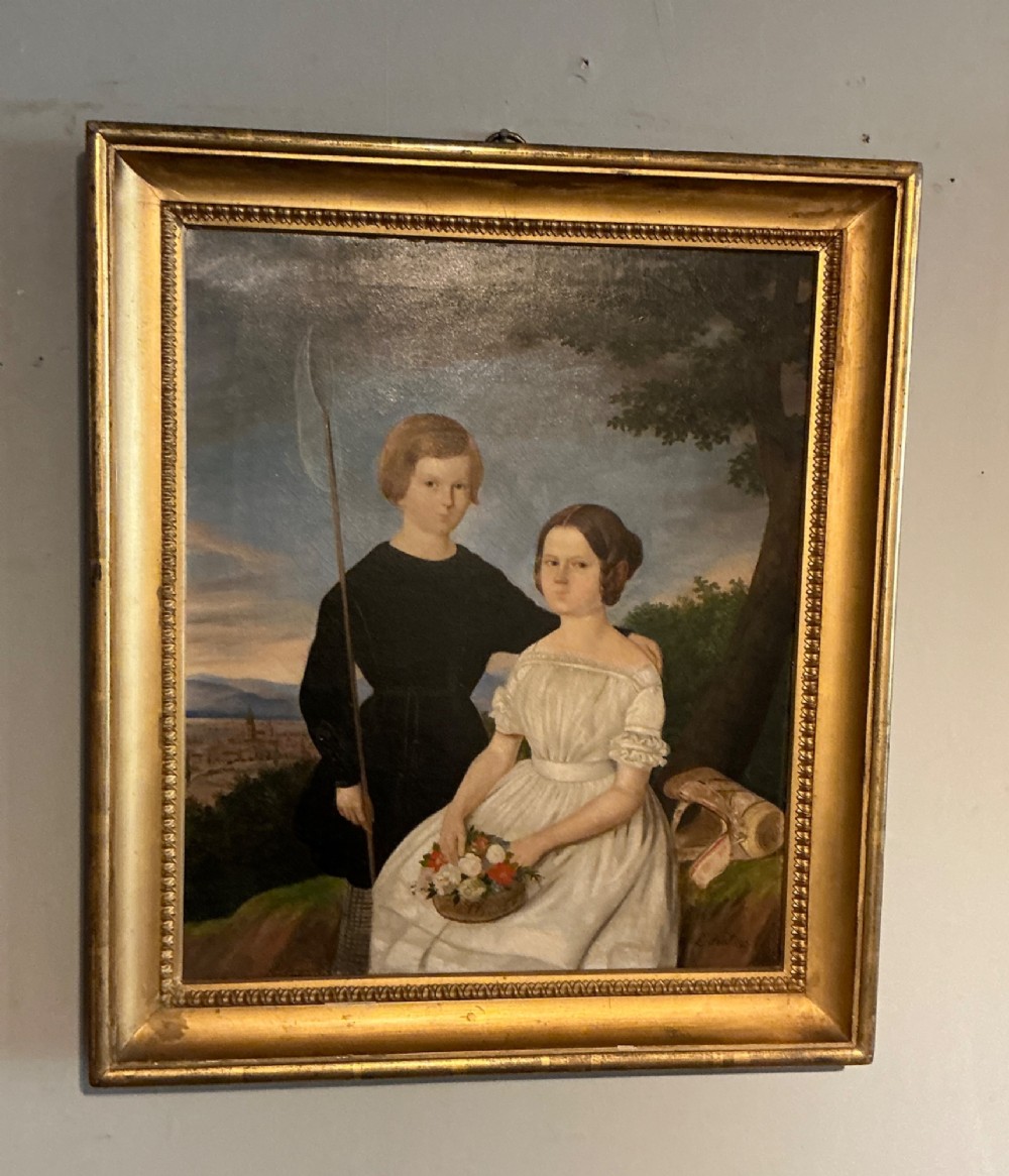 An early 19th-century oil painting depicting a boy in black clothing and a girl in a white dress seated outdoors, set within a gilded moulded frame.