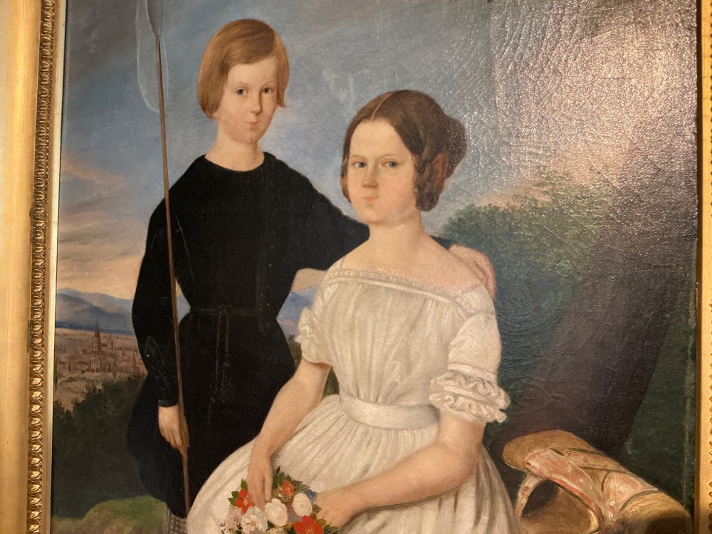 An early 19th-century oil painting depicting a boy in black clothing and a girl in a white dress seated outdoors, set within a gilded moulded frame. View V