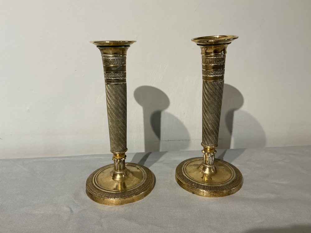 A pair of French Empire brass candlesticks with spiralled engine-turned shafts and circular bases.