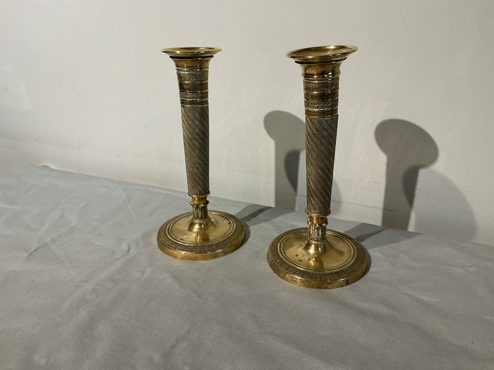 A pair of French Empire brass candlesticks with spiralled engine-turned shafts and circular bases. View II