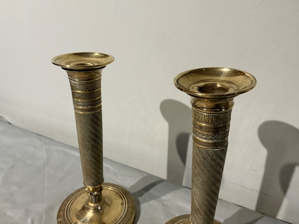 A pair of French Empire brass candlesticks with spiralled engine-turned shafts and circular bases. View V
