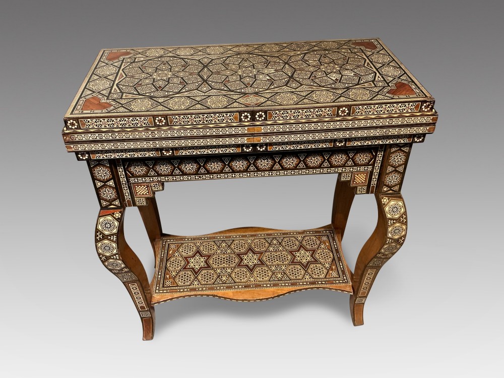 An antique Syrian Damascus games table featuring intricate geometric mother-of-pearl and wood inlay with cabriole legs and a matching lower shelf.