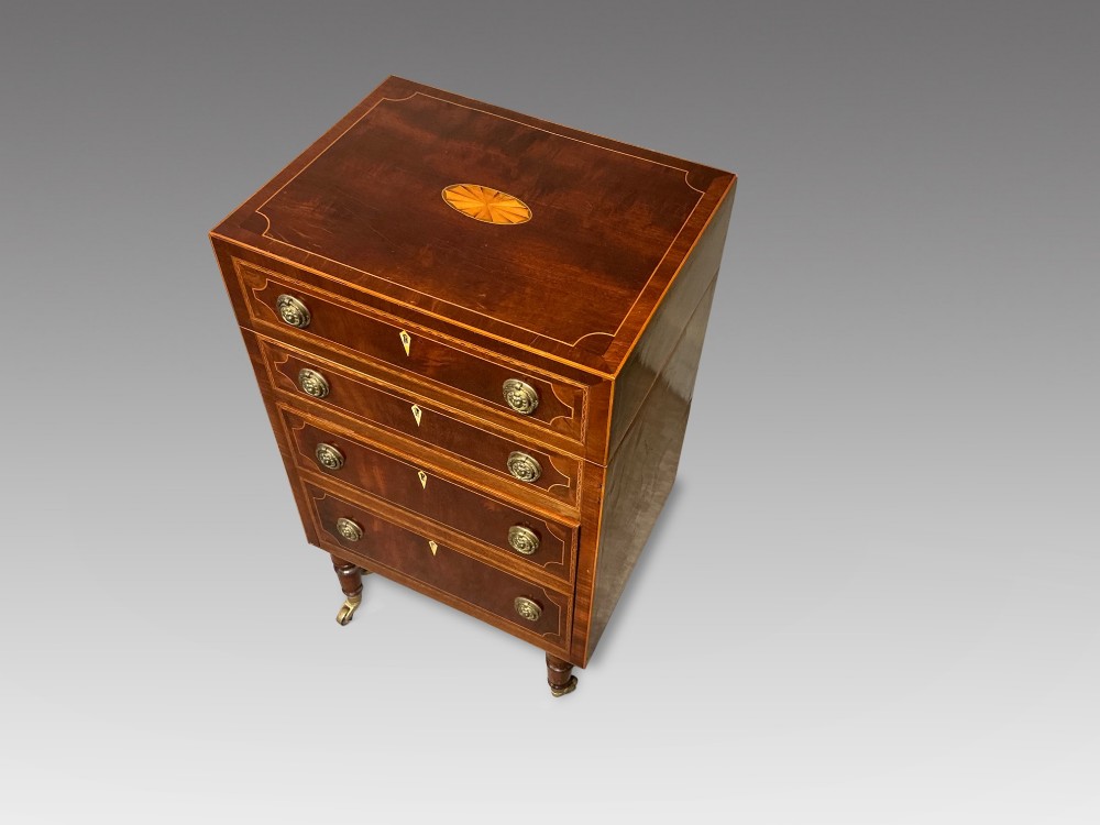 A nineteenth-century mahogany work table featuring satinwood inlay, bone escutcheons, brass ring handles, four drawer fronts, and turned legs on brass castors. View II
