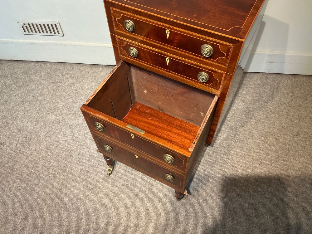 A nineteenth-century mahogany work table featuring satinwood inlay, bone escutcheons, brass ring handles, four drawer fronts, and turned legs on brass castors. View IV