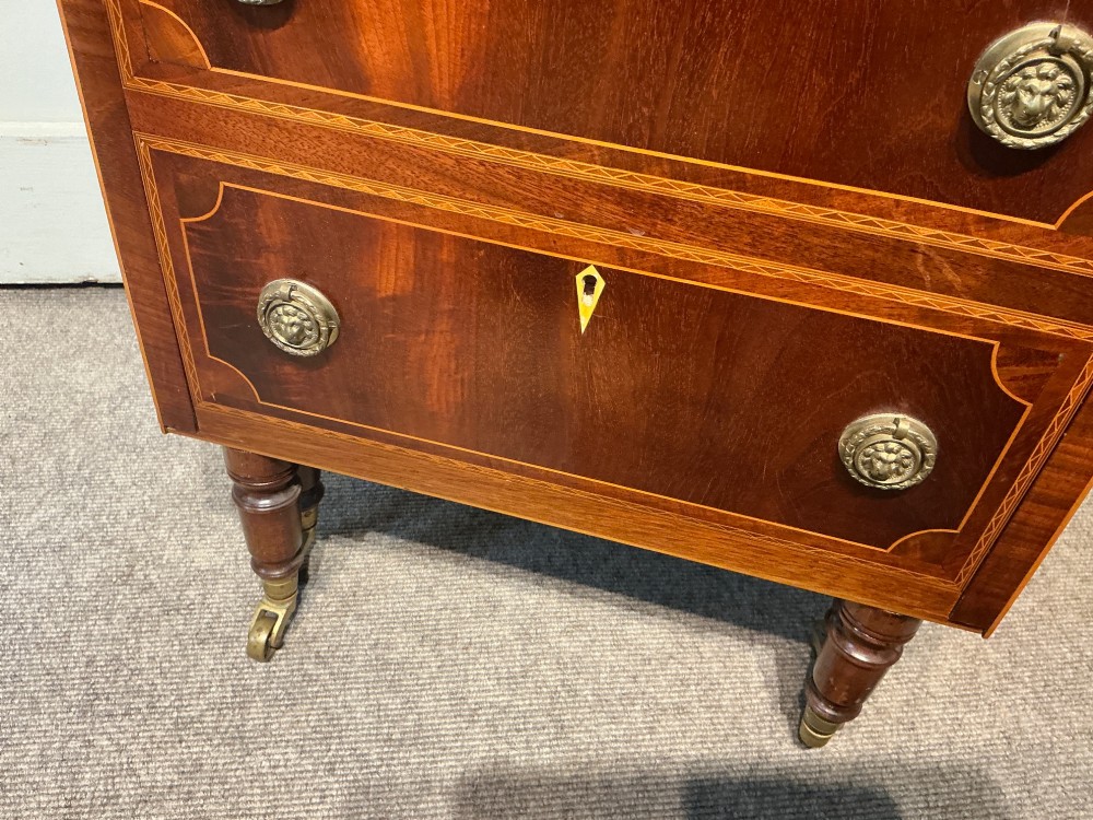 A nineteenth-century mahogany work table featuring satinwood inlay, bone escutcheons, brass ring handles, four drawer fronts, and turned legs on brass castors. View VI