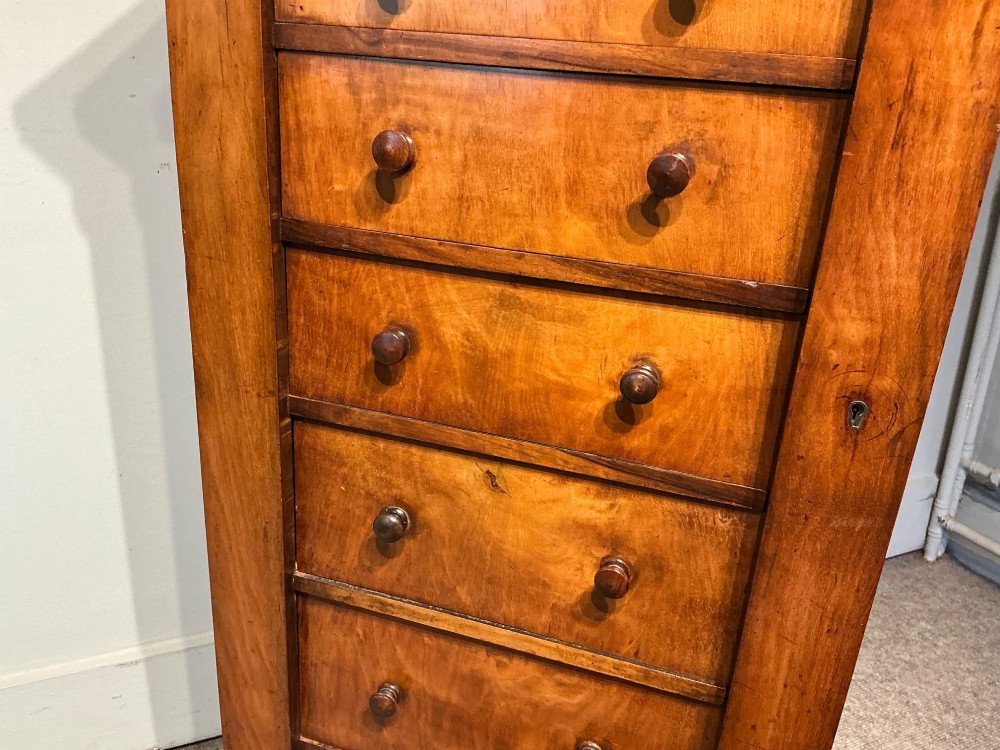 A tall, narrow Victorian walnut Wellington chest featuring seven stacked drawers with turned knobs, carved brackets, and a hinged locking pilaster. View V