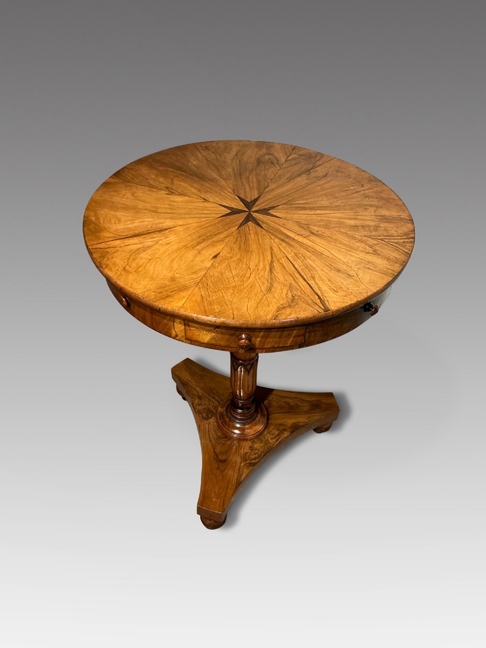 A circular antique Maltese olive wood drum table featuring a starburst veneered top with a central inlaid Maltese cross, supported on a turned central pedestal and a triform plinth base with bun feet. View II