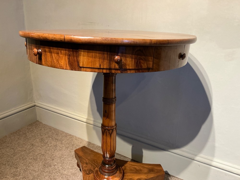 A circular antique Maltese olive wood drum table featuring a starburst veneered top with a central inlaid Maltese cross, supported on a turned central pedestal and a triform plinth base with bun feet. View VI
