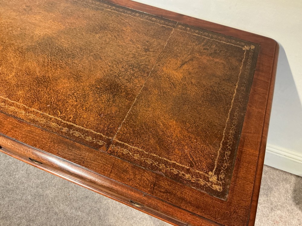 An antique mahogany writing table with a brown leather inset writing top, two frieze drawers with brass handles, and turned reeded legs on brass castors. View V