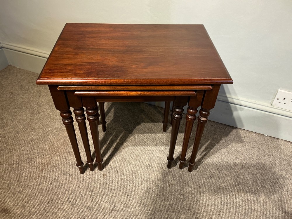 A set of three nested mahogany side tables featuring rectangular polished tops and slender turned legs. View III