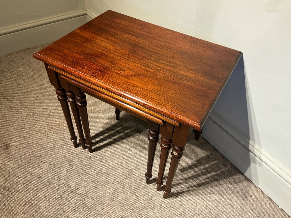 A set of three nested mahogany side tables featuring rectangular polished tops and slender turned legs. View IV
