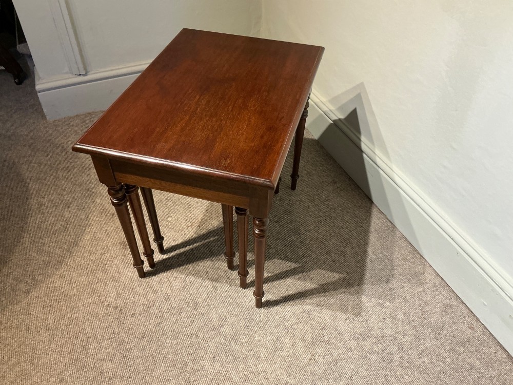 A set of three nested mahogany side tables featuring rectangular polished tops and slender turned legs. View VII