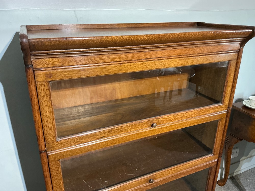A 1920s oak three-tier sectional bookcase featuring glazed lift-up doors and a single drawer at the base. View IV