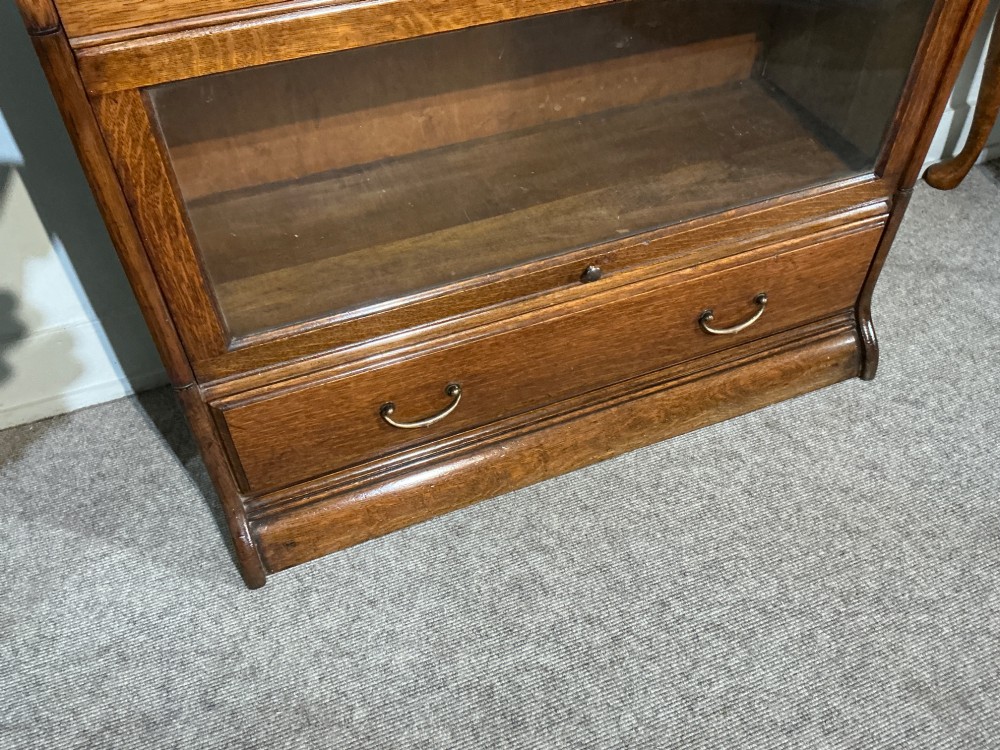 A 1920s oak three-tier sectional bookcase featuring glazed lift-up doors and a single drawer at the base. View VI