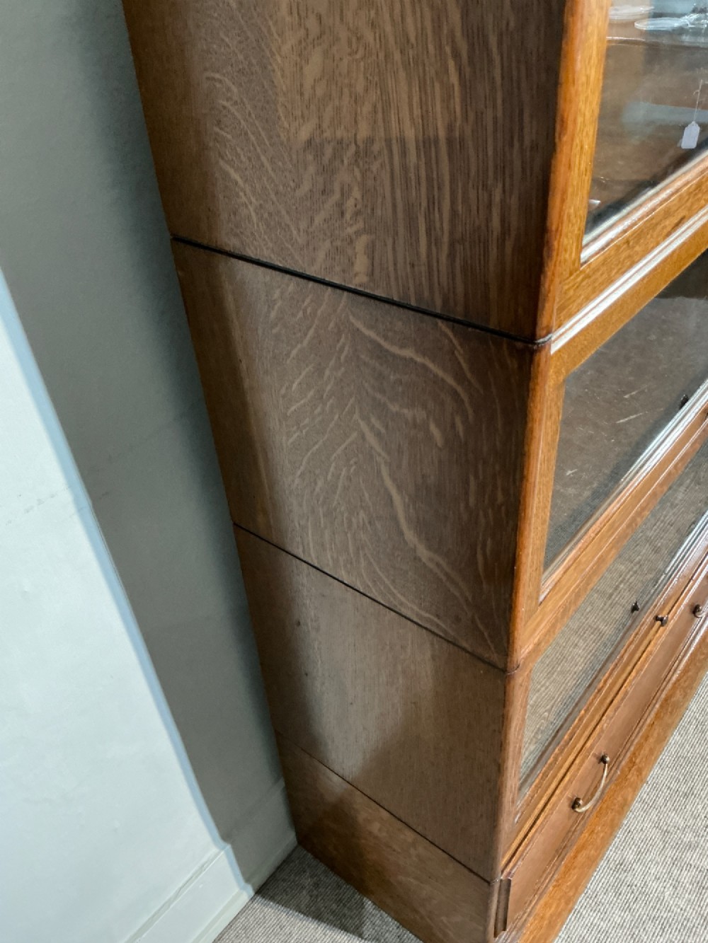 A 1920s oak three-tier sectional bookcase featuring glazed lift-up doors and a single drawer at the base. View VIII