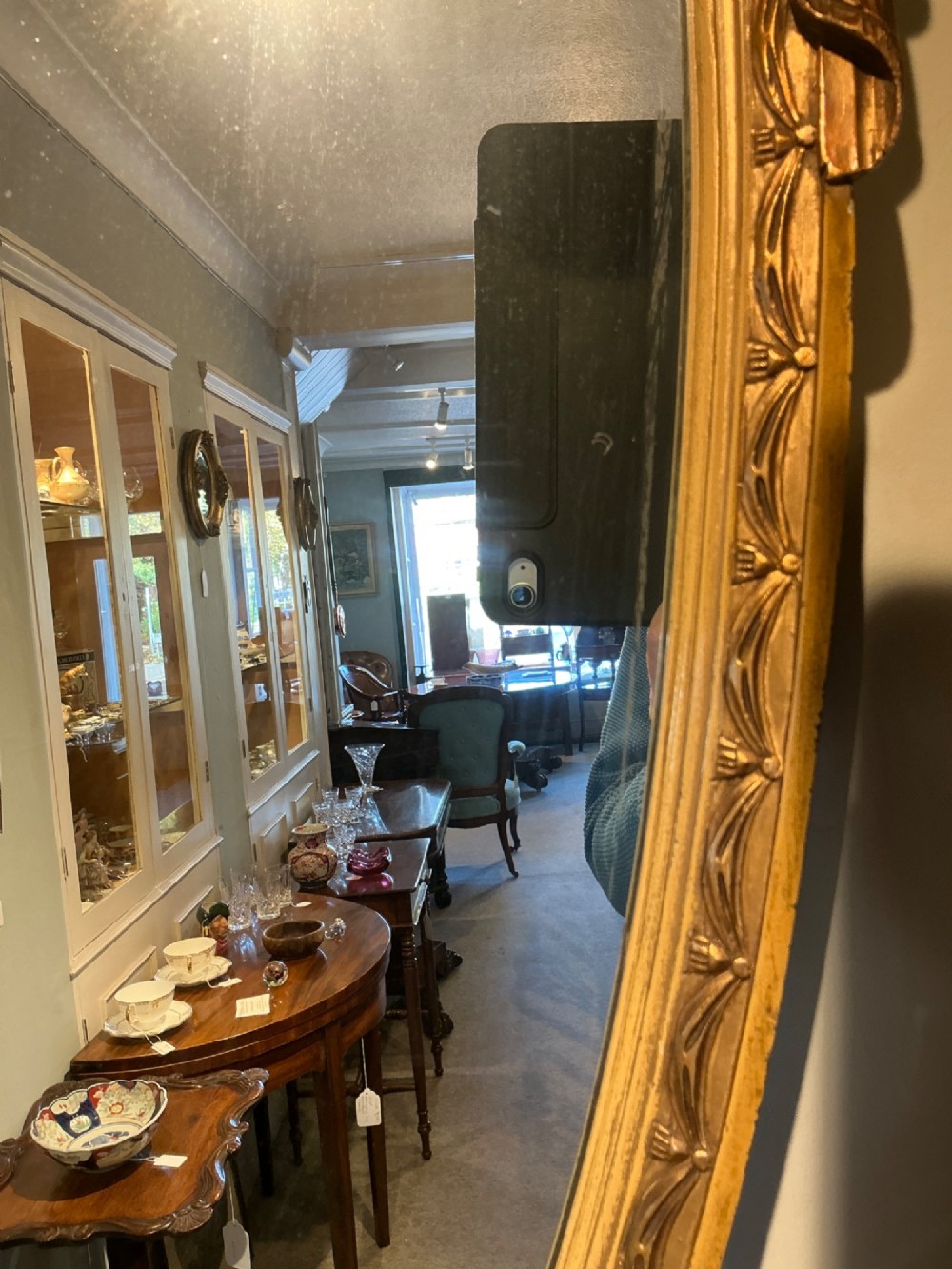 An Edwardian shield-shaped wall mirror featuring a giltwood frame decorated with carved draped swags and a central rosette crest. View VI