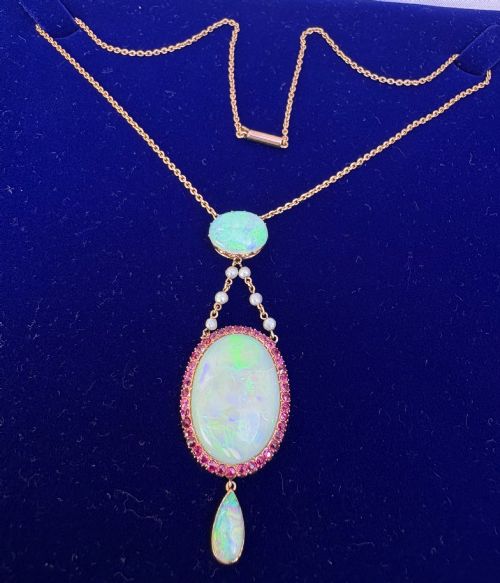 fig 1. An antique Victorian 15ct yellow gold lavalier pendant set with two oval cabochon opals, a halo of rubies, and seed pearl connectors.