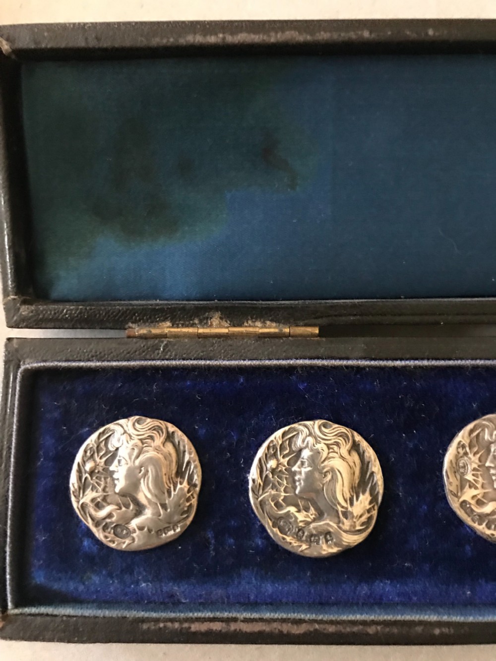 A set of six circular sterling silver Art Nouveau buttons featuring raised maiden profiles, presented inside a navy blue velvet-lined fitted box. View II