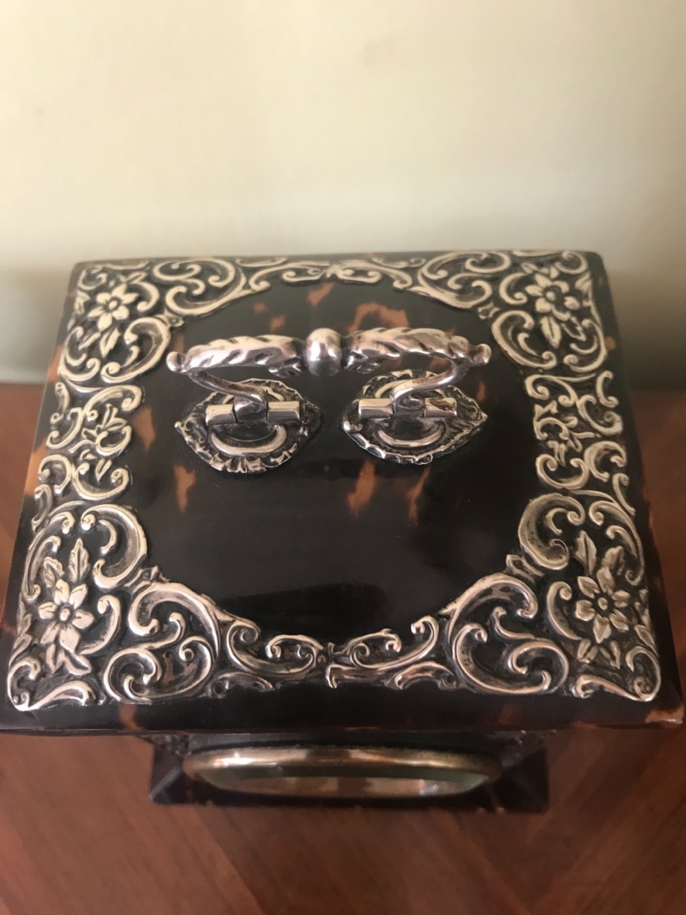 A 19th-century Victorian mantel clock featuring a dark tortoiseshell case, a silver front panel with floral scrollwork, a top carrying handle, and a white circular dial. View III